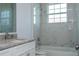 A bright bathroom features marble-style tile on the walls and floor, a tub, and a vanity at 508 Churchill Pl, Poinciana, FL 34759