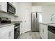 The kitchen features granite countertops, stainless steel appliances, white cabinetry and gray wood floors at 508 Churchill Pl, Poinciana, FL 34759