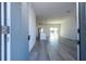 View of a living room with gray wood floors, white walls, and a kitchen with stainless steel appliances at 508 Churchill Pl, Poinciana, FL 34759
