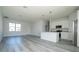 Bright living room with gray wood floors, white walls, stainless kitchen appliances and recessed lighting at 508 Churchill Pl, Poinciana, FL 34759
