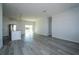 Open living room featuring gray wood floors, white walls and kitchen with stainless steel refrigerator at 508 Churchill Pl, Poinciana, FL 34759