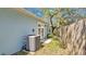 This home's backyard has a modern AC unit and a view of the trees and partial fencing at 5505 W Magnolia Ave, Port Orange, FL 32127