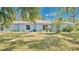 Beautiful single-story home with a vibrant blue exterior, lush greenery, and a welcoming front yard at 5505 W Magnolia Ave, Port Orange, FL 32127