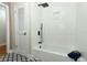 Bathroom with tub, shower head and white tiled walls, and black hardware and patterned tile flooring at 656 Lake Charm Dr, Oviedo, FL 32765