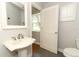 Well-lit bathroom featuring a pedestal sink, toilet, shuttered window, and a door to the exterior at 656 Lake Charm Dr, Oviedo, FL 32765