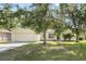 Traditional home with a two-car garage, lush lawn, and mature shade trees at 672 Reindeer Dr, Kissimmee, FL 34759