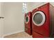 Bright laundry room featuring side-by-side red washer and dryer with tile floors and a small window at 8245 Laureate Blvd, Orlando, FL 32827