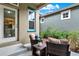 Outdoor patio sitting area features two chairs with throw pillows and a table with green garden views at 8245 Laureate Blvd, Orlando, FL 32827