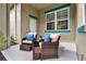 Cozy outdoor patio features comfortable wicker chairs, foot rests and a small table on a rug at 8245 Laureate Blvd, Orlando, FL 32827