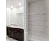 Bathroom featuring double sinks, granite countertop, dark cabinets, and a shelving unit at 856 Teton St, Haines City, FL 33844