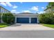 Detached two-car garage with blue doors and a concrete driveway surrounded by green bushes at 8692 Tavistock Lakes Blvd, Orlando, FL 32827