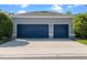 Attached two-car garage with blue doors and a concrete driveway lined with manicured bushes at 8692 Tavistock Lakes Blvd, Orlando, FL 32827