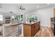 Modern kitchen island is open to a living room with hardwood floors and stainless steel appliances at 8692 Tavistock Lakes Blvd, Orlando, FL 32827