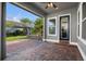 Covered back patio with ceiling fan, brick pavers, and lush landscaping at 8692 Tavistock Lakes Blvd, Orlando, FL 32827