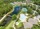 An aerial view featuring a luxurious pool, walking path, tennis courts and lake in a lush, green neighborhood at 9330 Shadow Pinar Ct, Orlando, FL 32825