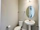 Powder room with pedestal sink, oval mirror, and neutral wall color at 9917 Summerlake Groves St, Winter Garden, FL 34787
