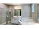 Bright bathroom features a glass-enclosed shower and a soaking tub with white cabinets and countertop at 9917 Summerlake Groves St, Winter Garden, FL 34787