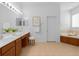 Bright bathroom featuring double sinks, vanity with stool, soaking tub, and neutral tiling at 10125 Sandy Marsh Ln, Orlando, FL 32832