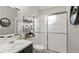 This bathroom has a white toilet and sink with a frosted glass shower and floating shelves at 10169 Matchlock Dr, Orlando, FL 32821