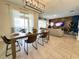 Open-concept dining area featuring a long wooden table, modern chairs, and seamless flow into the living room at 1077 Leader St, Davenport, FL 33896