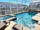 Relaxing screened-in pool with spa, lounge chairs, and views of surrounding houses at 1077 Leader St, Davenport, FL 33896