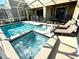 Backyard pool and spa with lounge chairs for relaxation in a screened enclosure at 1077 Leader St, Davenport, FL 33896