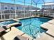Relaxing screened-in pool with spa, lounge chairs, and views of surrounding houses at 1077 Leader St, Davenport, FL 33896