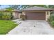 Single-story house featuring a brown garage door, a manicured lawn, and a paved driveway at 11 Huntley Ct, Haines City, FL 33844