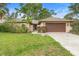 Inviting single-story home with a lush green lawn, mature trees, and a spacious driveway at 11 Huntley Ct, Haines City, FL 33844