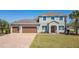 Charming two-story home featuring a three-car garage, lush lawn, and manicured landscaping at 14537 San Lorenzo Dr, Orlando, FL 32820