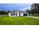 Attractive single-story home featuring a manicured lawn, modern design, and a dark garage door at 16734 Sw 18Th Avenue Rd, Ocala, FL 34473