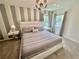 Bedroom with carpet, large bed, modern chandelier, and neutral striped accent wall at 2034 Fleming Mist Pl, Kissimmee, FL 34747
