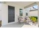 Inviting front porch featuring a dark door, seating, neutral decor, and lush landscaping at 2294 Gold Dust Dr, Minneola, FL 34715