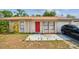 Close up of single-story home with a red front door and driveway with a vehicle parked in front at 3711 Shady Grove Cir, Orlando, FL 32810