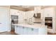 Well-lit kitchen featuring white cabinets, a large island, stainless steel appliances, and stylish pendant lights at 4204 Barbuda Ln, Kissimmee, FL 34758