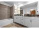 Bright bathroom with dual sinks, tub, vanity and neutral tile at 4375 Scene Ln, Kissimmee, FL 34746