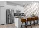 Modern kitchen featuring stainless steel appliances, light countertops, floral accent wall and breakfast bar seating at 4375 Scene Ln, Kissimmee, FL 34746