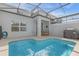 Backyard pool with a screened enclosure, complete with a patio table, chairs, and grill at 4375 Scene Ln, Kissimmee, FL 34746