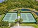 Aerial view of tennis courts surrounded by lush greenery and a pond at 4608 Atwood Dr, Orlando, FL 32828
