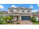 Inviting two-story home with a brick driveway, complemented by lush landscaping and solar panels at 4783 Riverwalk Dr, St Cloud, FL 34771