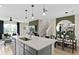 Modern kitchen features an island, stainless steel sink, pendant lights, and dining area with a striking round mirror at 7274 Summer Ivy Aly, Orlando, FL 32829