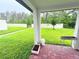 Patio view of the lush backyard with green grass and a white fence at 877 Rivers Crossings St, Clermont, FL 34714