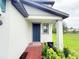 View of the front porch with a blue front door with brick pavers and green shrubbery at 877 Rivers Crossings St, Clermont, FL 34714