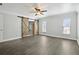 Bright bedroom features sleek floors, a ceiling fan, and a sliding barn door to another room at 949 Shadow Oaks Rd, Kissimmee, FL 34744