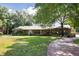 A beautifully landscaped front yard leading up to a cozy ranch-style house featuring a metal roof at 949 Shadow Oaks Rd, Kissimmee, FL 34744