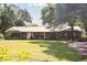 One-story home boasting a well-manicured lawn, metal roof, and verdant mature trees enhancing curb appeal at 949 Shadow Oaks Rd, Kissimmee, FL 34744