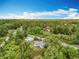 Aerial view highlighting the property nestled among lush greenery, with a visible road and blue sky above at 9506 Number Two Rd, Howey In The Hills, FL 34737