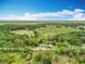 Aerial view showcasing the property's expansive landscape, with open fields and wooded areas under a partly cloudy sky at 9506 Number Two Rd, Howey In The Hills, FL 34737