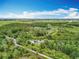 An aerial view of the property showing its placement surrounded by trees, farmland, and other structures under the sky at 9506 Number Two Rd, Howey In The Hills, FL 34737