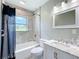 The bathroom features tile surround, a shower-tub combo and vanity with white cabinets at 9506 Number Two Rd, Howey In The Hills, FL 34737